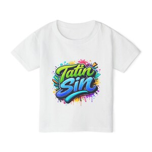 May include: White t-shirt with the words "Tatin Sin" in a vibrant graffiti-style design. The text is in green and blue with a black outline, set against a backdrop of colourful paint splatters.