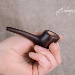 May include: A dark brown wooden pipe with a round bowl and a long, curved stem.