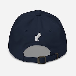 Könnte beinhalten: Eine marineblaue Baseballkappe mit einem weißen gestickten Umriss des Bundesstaates Maine auf der Rückseite.