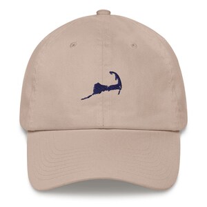 Puede incluir: Una gorra de béisbol beige con un contorno bordado de Cape Cod en azul marino.