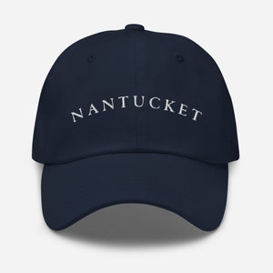 Può includere: Un cappello da baseball blu navy con testo ricamato in bianco che recita "NANTUCKET".