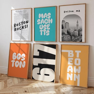 May include: Six framed art prints with wooden frames. The prints feature text and images related to Boston, Massachusetts. One print is a newspaper clipping with "BOSTON ROCKS!". Other prints have "MASSACHUSETTS", "BOSTON, MA", "617", and "BOSTON" in bold text.