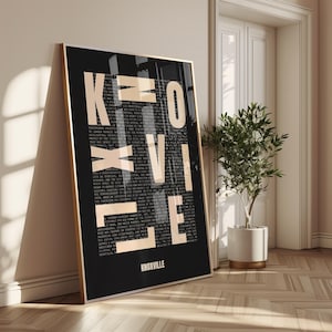 May include: A framed art print featuring the word "KNOXVILLE" in large, cream-colored letters against a black background. The letters are partially transparent, revealing smaller text. The frame is gold. The word "KNOXVILLE" is also printed at the bottom.