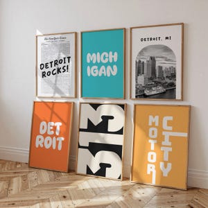 Puede incluir: Seis impresiones artísticas enmarcadas con temática de Detroit. Las impresiones presentan textos como "DETROIT ROCKS!", "MICHIGAN" y "313", junto con un paisaje urbano en blanco y negro y las palabras "MOTOR CITY". Los marcos son de color marrón claro.