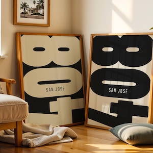 May include: Two framed art prints with a minimalist design. Each print features the number "807" in black against a cream background, with "SAN JOSE" printed below. The frames are made of light-colored wood, adding a touch of warmth.