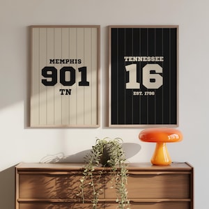 May include: Two framed prints with text. The left print has a beige background with vertical lines and reads "MEMPHIS 901 TN". The right print has a black background with vertical lines and reads "TENNESSEE 16 EST. 1796".