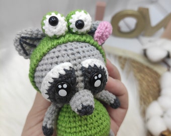 Crochet raccoon in a frog costume. Raccoon amigurumi toy. Keychain raccoon amigurumi