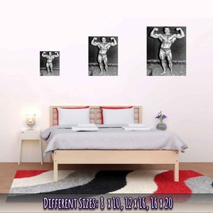 Op de afbeelding: Zwart-witfoto van een bodybuilder die poseert met zijn armen omhoog. De foto is ingelijst en hangt aan een witte muur boven een bed met witte beddengoed. De tekst "DIFFERENT SIZES: 8 X 10, 12 X 16, 16 X 20" is onder de afbeelding gedrukt.