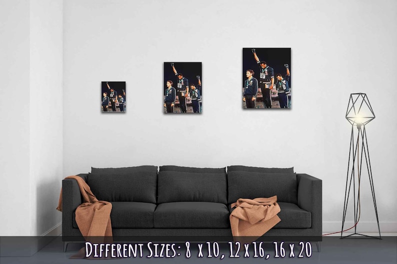 Puede incluir: Una fotograf&iacute;a en blanco y negro de tres atletas levantando el pu&ntilde;o en el aire. Los atletas llevan ch&aacute;ndales azules y est&aacute;n de pie en un podio. La imagen est&aacute; disponible en diferentes tama&ntilde;os: 20,3 x 25,4 cm, 30,5 x 40,6 cm, 40,6 x 50,8 cm.