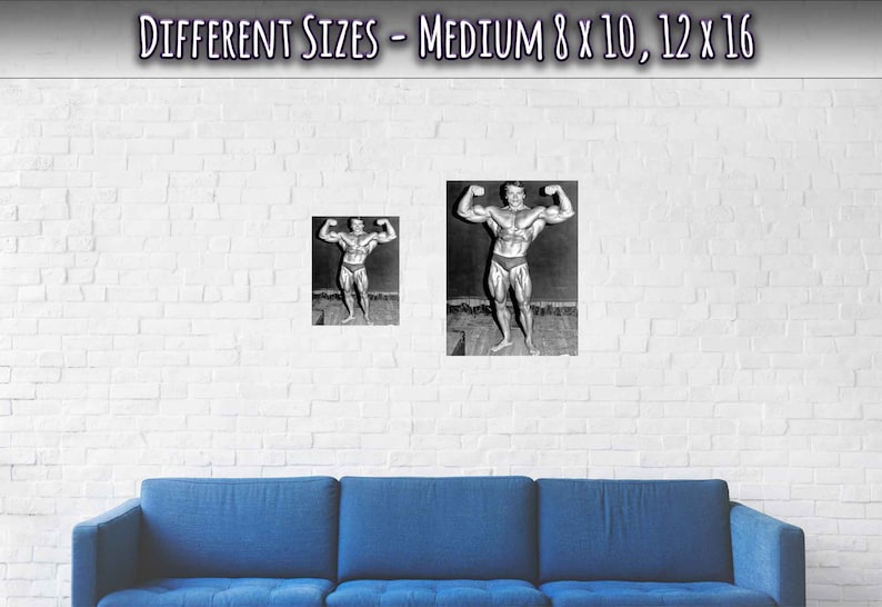 Op de afbeelding: Een zwart-witfoto van een bodybuilder die poseert met zijn armen omhoog. De foto is ingelijst en hangt aan een witte bakstenen muur boven een blauwe bank.