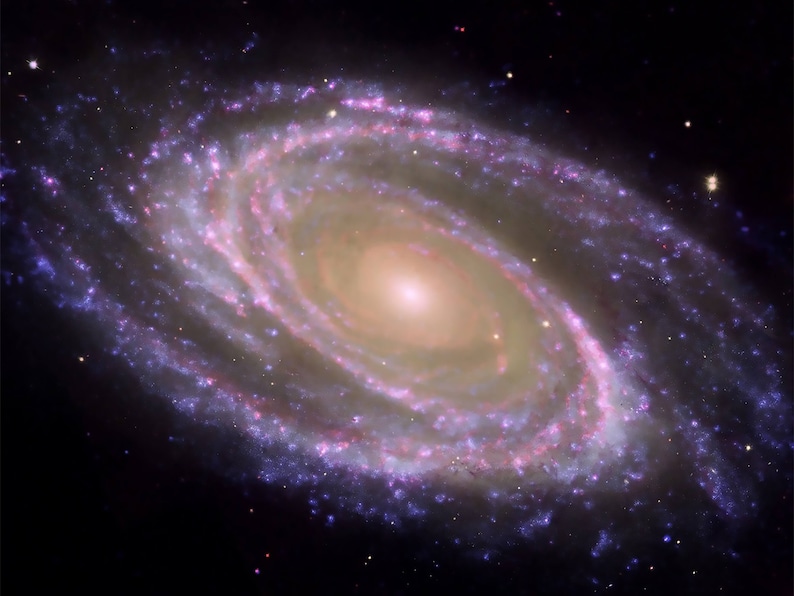 Pode incluir: Uma gal&aacute;xia espiral com um n&uacute;cleo brilhante amarelado e bra&ccedil;os em espiral de estrelas e g&aacute;s. A gal&aacute;xia est&aacute; sobre um fundo escuro do espa&ccedil;o.