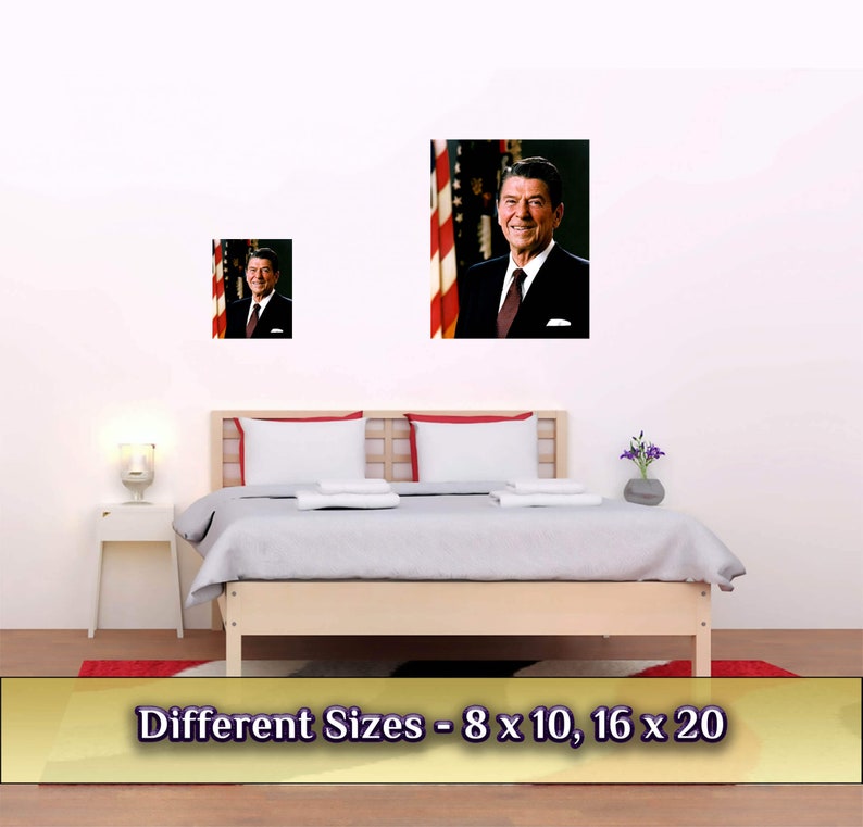 May include: A framed photograph of Ronald Reagan, the 40th President of the United States, standing in front of an American flag. The image is displayed on a white wall above a bed with white bedding. The text "Different Sizes - 8 x 10, 16 x 20" is displayed below the image.
