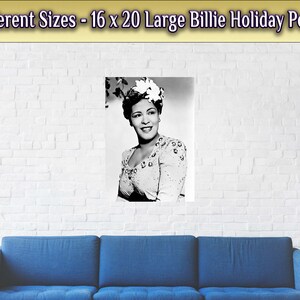 May include: Black and white photo of Billie Holiday, a famous jazz singer, wearing a white flower in her hair. The photo is printed on a poster with a white brick wall background.