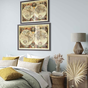 May include: Two framed vintage world maps in brown frames hanging on a light blue wall above a bed with a green and white patterned duvet and yellow throw pillows. A wicker side table with a lamp and dried flowers is on the right side of the bed.