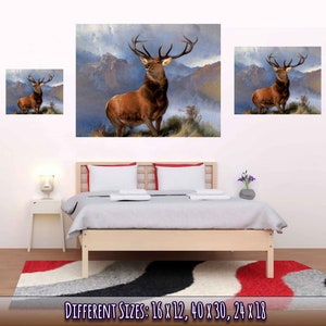 Peut inclure: Une peinture repr&eacute;sentant un cerf rouge debout dans un paysage montagneux. Le cerf a de grands bois et regarde vers la droite. L'arri&egrave;re-plan est de couleur bleu-gris brumeux avec des montagnes au loin. La peinture est encadr&eacute;e et accroch&eacute;e au mur au-dessus d'un lit.