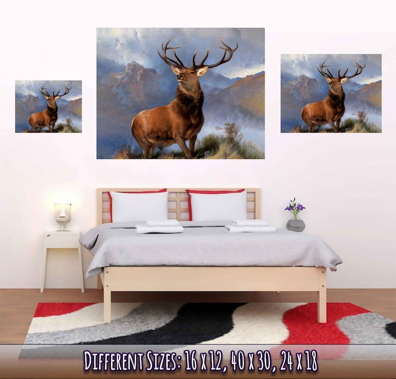 Peut inclure: Une peinture repr&eacute;sentant un cerf rouge debout dans un paysage montagneux. Le cerf a de grands bois et regarde vers la droite. L'arri&egrave;re-plan est de couleur bleu-gris brumeux avec des montagnes au loin. La peinture est encadr&eacute;e et accroch&eacute;e au mur au-dessus d'un lit.