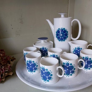May include: A white tea set with a blue and green floral pattern. The set includes a teapot, creamer, sugar bowl, and six cups.