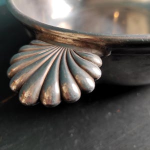 May include: A silver serving bowl with a scalloped edge and a shell-shaped handle.