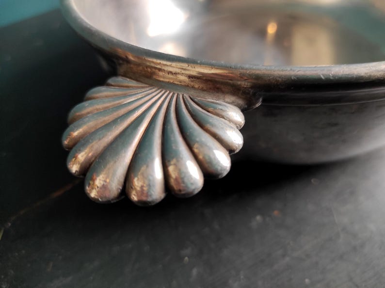 May include: A silver serving bowl with a scalloped edge and a shell-shaped handle.