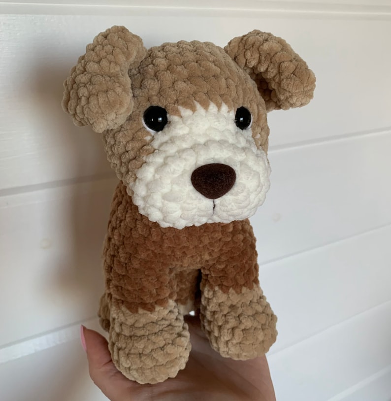 May include: A brown and white crocheted stuffed dog toy with black eyes and a brown nose.