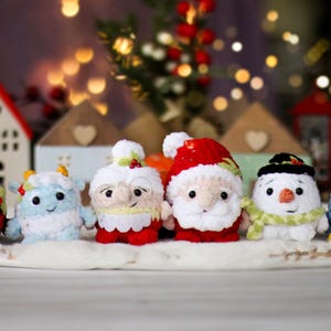 Peut inclure: Une collection de six décorations de Noël en crochet, dont le Père Noël, un bonhomme de neige, un pingouin, un renne, un gnome et un bonhomme en pain d'épices. Les décorations sont toutes blanches avec des accents rouges, verts et bleus.