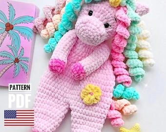 May include: A pink crocheted unicorn amigurumi toy with a rainbow yarn mane and tail. The unicorn has a yellow flower on its side and a star on the ground. The pattern is available as a PDF download.