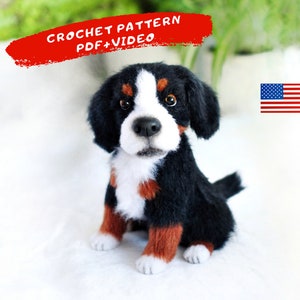 May include: Crochet pattern for a Bernese Mountain Dog puppy. The pattern includes a PDF and video instructions. The puppy is sitting and looking at the camera. The puppy is black, white, and brown.