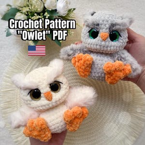 Op de afbeelding: Twee gehaakte uilenspeeltjes, één lichtgrijs en één crèmekleurig, met oranje voeten en grote, expressieve ogen. De tekst "Crochet Pattern 'Owlet' PDF" wordt boven de uilen weergegeven, samen met de Amerikaanse vlag.