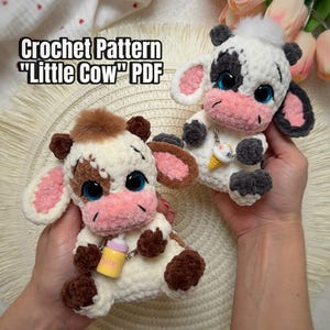 May include: Two plush crochet cow toys with large blue eyes and pink muzzles. One cow is cream with brown patches and a brown tuft, holding a yellow milk bottle. The other is white with black patches and a white tuft, holding an ice cream cone. Text: Crochet Pattern "Little Cow" PDF.