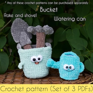 May include: A set of three crochet patterns for a bucket, rake and shovel, and watering can. The bucket is light blue with a smiling face and arms. The rake and shovel are gray and brown. The watering can is light blue with a smiling face.