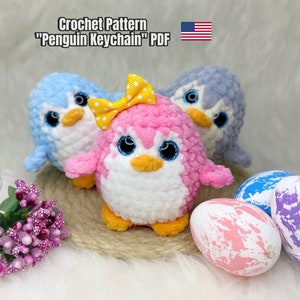 Puede incluir: Patrón de crochet para un llavero de pingüino. El patrón incluye instrucciones para hacer un pingüino rosa con un lazo amarillo, un pingüino azul y un pingüino gris. El patrón está disponible para descargar en PDF.