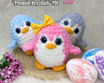 May include: Crochet pattern for a penguin keychain. The pattern includes instructions for making a pink penguin with a yellow bow, a blue penguin, and a gray penguin. The pattern is available as a PDF download.