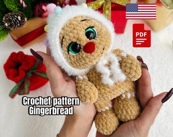 May include: A handmade, plush gingerbread man doll with a white hood and scarf, green eyes, and a red nose. The doll is held in a person's hands, with the text "Crochet pattern Gingerbread" visible.