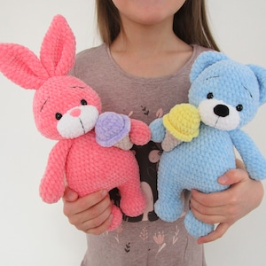 May include: A pink crocheted bunny holding a purple ice cream cone and a blue crocheted bear holding a yellow ice cream cone.