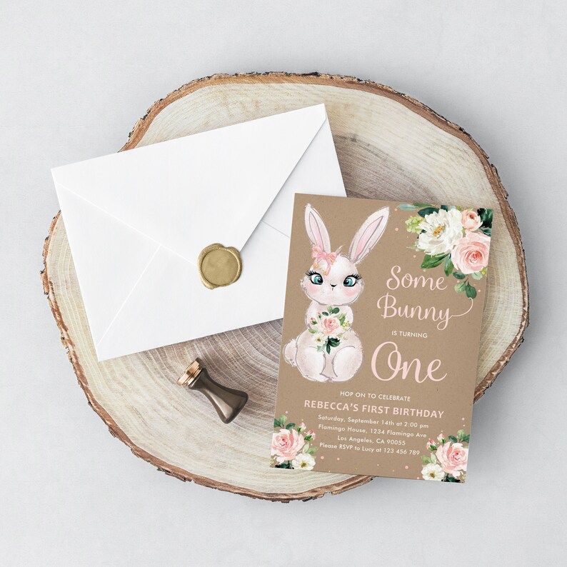 May include: A brown invitation card with a white bunny illustration holding pink flowers. The text reads "Some Bunny is turning One. Hop on to celebrate Rebecca's First Birthday. Saturday, September 14th at 2:00 pm. Flamingo House, 1234 Flamingo Ave. Los Angeles, CA 90055. Please RSVP to Lucy at 123 456 789."