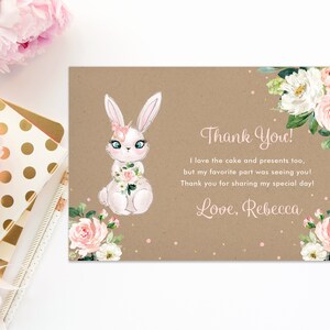 May include: Thank you card with a white bunny holding pink flowers, surrounded by pink and white flowers on a brown background. The text reads "Thank You! I love the cake and presents too, but my favorite part was seeing you! Thank you for sharing my special day! Love, Rebecca."