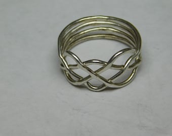 Könnte beinhalten: Ein silberner Ring mit einem geflochtenen Design. Der Ring besteht aus mehreren Metallsträngen, die miteinander verflochten sind, um ein komplexes Muster zu erzeugen.