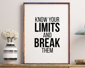 May include: A motivational quote in a black frame on a white wall reads "Know your limits and break them". The frame is on a light blue and white cabinet with a vase of white flowers.