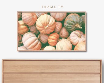 May include: A rectangular television screen with a light wood frame displaying a high-resolution image of various pumpkins in shades of orange, green, and cream. Below the screen is a light wood dresser with three horizontal drawers.