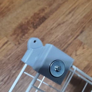 May include: A gray 3D printed bracket with a metal screw attached to a white wire rack.