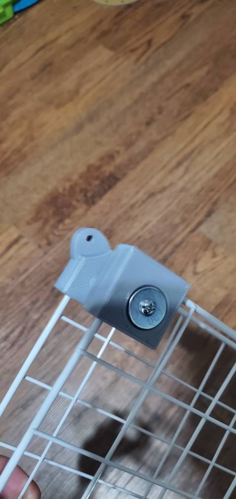 May include: A gray 3D printed bracket with a metal screw attached to a white wire rack.