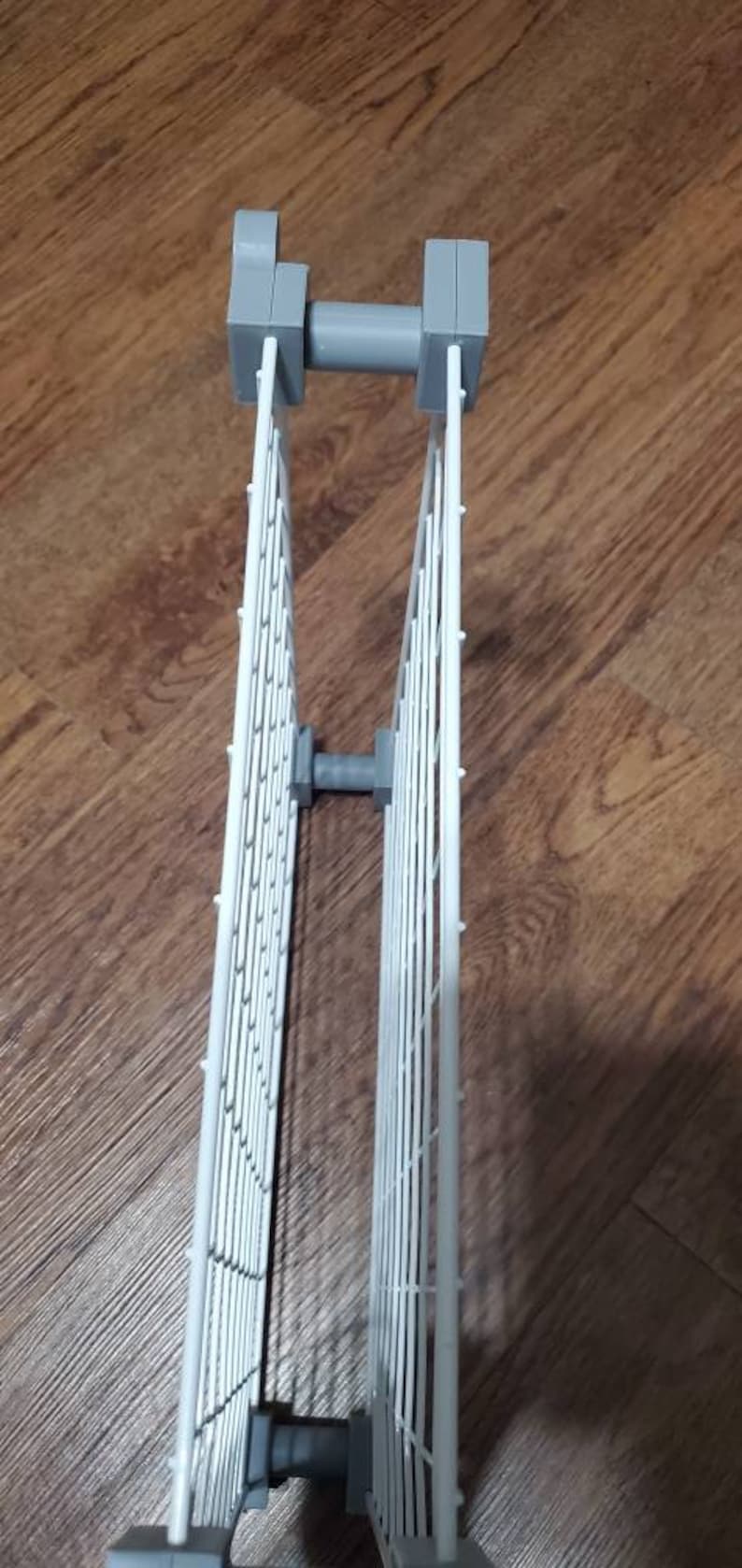 May include: A white metal expandable shelf unit with gray plastic connectors. The shelf unit is made of a grid pattern and can be adjusted to different sizes.