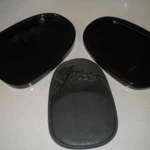 以下が含まれることがあります： 黒い墨石が3つ、2つは丸型、1つは彫刻が施された楕円形です。