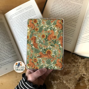 Peut inclure: Une coque de téléphone à motif vert et orange avec un motif répété de tigres, de tournesols et de champignons.