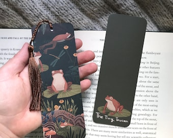 Bokmärke med träskgroda. Orangea grodor på näckrosblad, svampar, trollslända, Cottagecore, Witchy, Goblincore, med eller utan tofs.