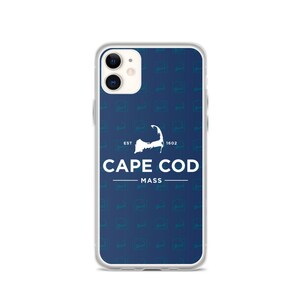 Peut inclure: Coque de téléphone transparente avec un fond bleu orné d'un motif répété du contour de Cape Cod. Le boîtier affiche le texte "CAPE COD MASS" en blanc, avec "EST 1602" au-dessus du contour.
