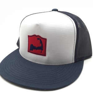 Puede incluir: Gorra de camionero blanca y azul marino con un parche rojo bordado de la silueta de Cape Cod.