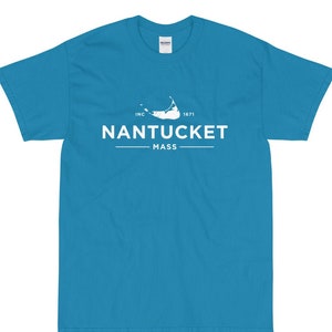 Könnte beinhalten: Ein türkisfarbenes T-Shirt mit einem weißen Grafikdesign, das den Text "NANTUCKET MASS" und eine stilisierte Umrandung einer Insel zeigt. Der Text "INC 1671" ist ebenfalls im Design enthalten.