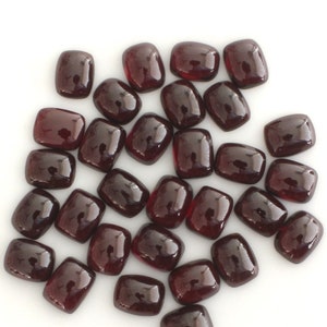 Könnte beinhalten: Ein Haufen von 30 losen, dunkelroten, rechteckigen Edelstein-Cabochons. Die Cabochons sind glatt und poliert.