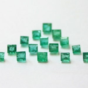 May include: A selection of square-cut emerald gemstones, each with a vivid green colour. The gemstones are arranged on a white surface, creating a visually appealing display. The image showcases the gemstones' clarity and colour, highlighting their quality.